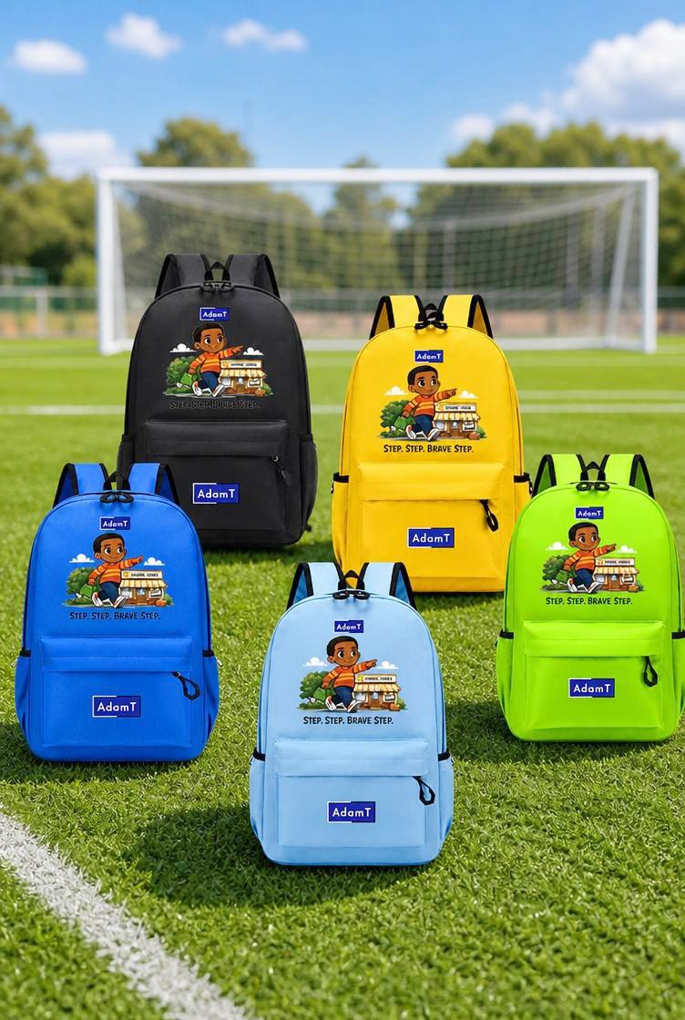 Five backpacks in black, yellow, blue, light blue, and lime green are arranged on a grassy soccer field with a goal in the background. Each backpack features a colorful cartoon graphic and a blue 'Adam' brand patch on the front.